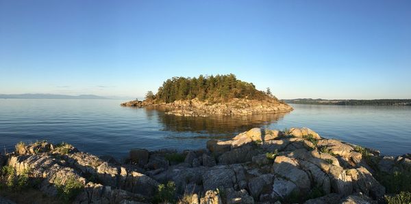 Scenic view of rocks in sea against clear blue sky