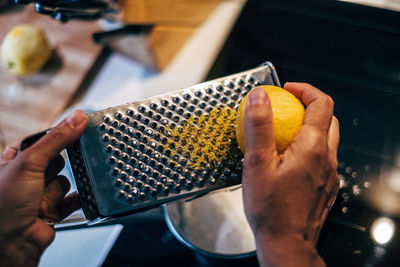 High angle view of human hand grating lemon