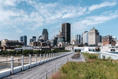 Road by buildings in city against sky