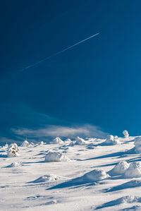 Snow covered landscape against blue sky