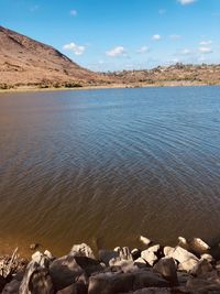 Scenic view of sea by mountain against sky