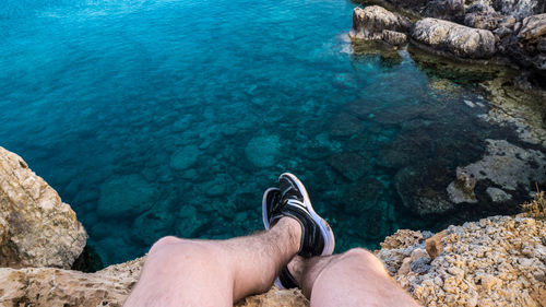 Low section of person on rock by sea