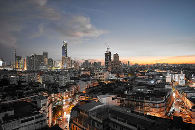 Illuminated cityscape against sky during sunset