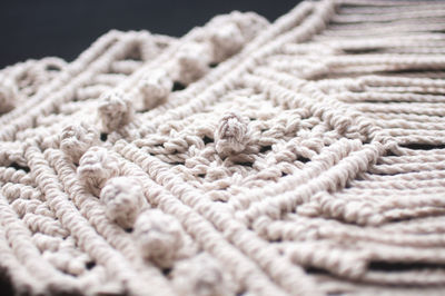 Macrame ornament from white natural cotton threads on a black background.