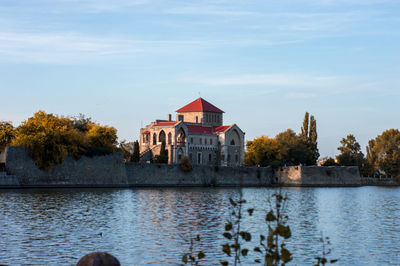 Houses by lake and buildings against sky