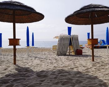 Deck chairs on beach against sky