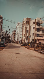 Road by buildings in city against sky