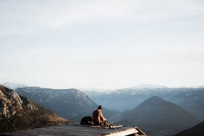 Rear view of man on rock against sky