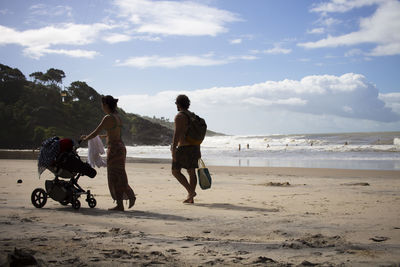 People walking at beach against sky