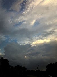 Low angle view of silhouette trees against cloudy sky