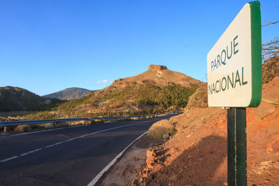 Road sign against mountain and blue sky