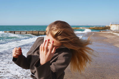 Beautiful young girl with flying hair at the winter sea shore. person