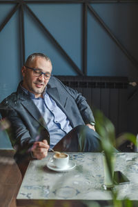 Businessman with coffee cup on table sitting in cafe