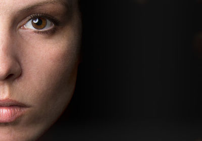 Close-up portrait of a serious young woman over black background