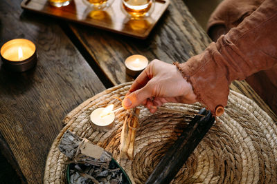 Lighting up candles on the table with matches. women hand holding fire. cozy evening home decoration