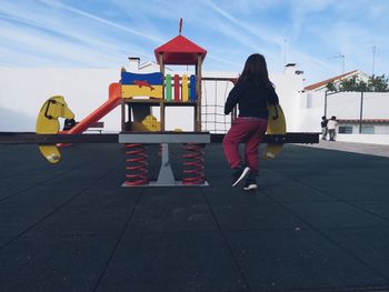 Rear view of girl standing by play equipment