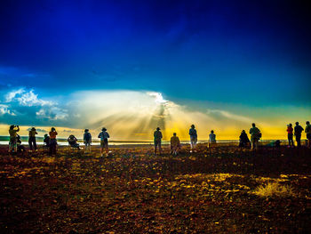 Silhouette of people on field against cloudy sky