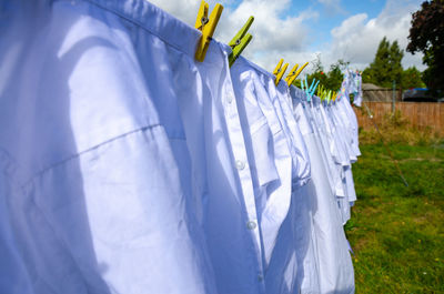 Shirts drying on clothesline against sky