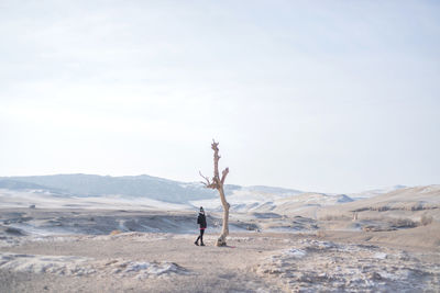 Man with arms raised on mountains against sky