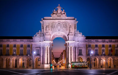 Statue in illuminated city against clear sky at night