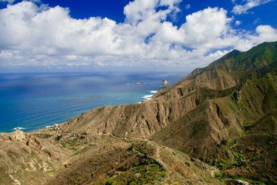 View of mountains and blue sea against cloudy sky