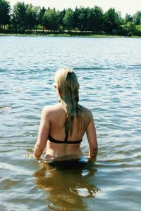 Rear view of shirtless young woman in lake