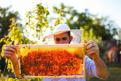 Close-up of man holding bee hive at farm