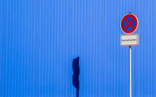 Close-up of no parking sign on blue wall