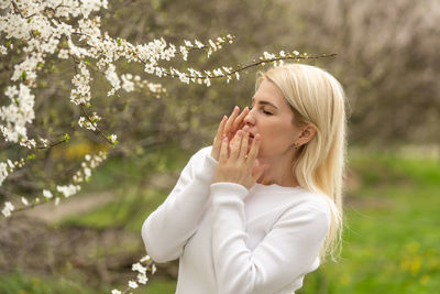 Woman sneezing by flowering tree