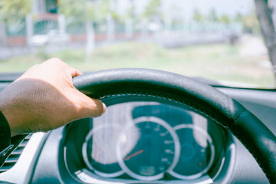 Cropped hand of man holding steering wheel