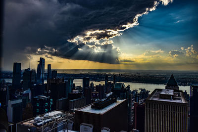 Aerial view of buildings by sea against sky during sunset