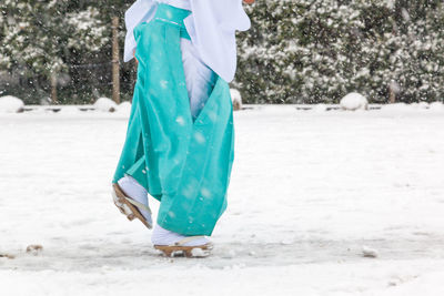 Low section of person walking on snow covered landscape