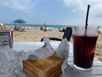 Lounge chairs and table at beach against sky