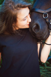 Close-up of young woman kissing horse while standing outdoors
