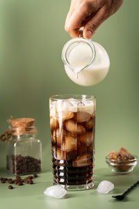 Close-up of hand holding drink on table