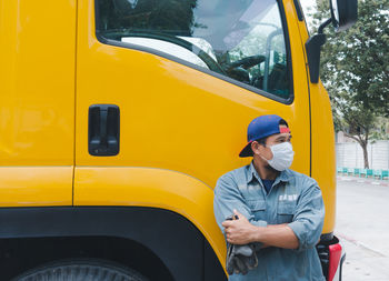 Full length of man standing on yellow car