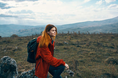 Young woman standing on mountain against sky