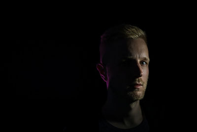 Portrait of young man against black background