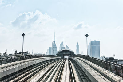 Railroad tracks in city against cloudy sky