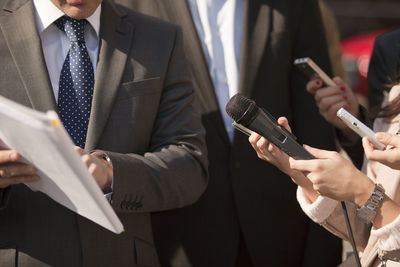 Midsection of man holding mobile phone