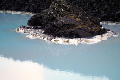 High angle view of volcanic rocks on blue lagoon