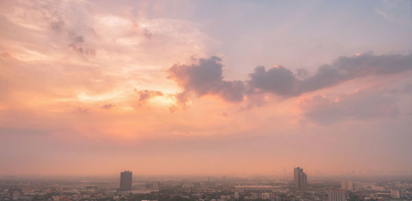 Aerial view of buildings against cloudy sky during sunset