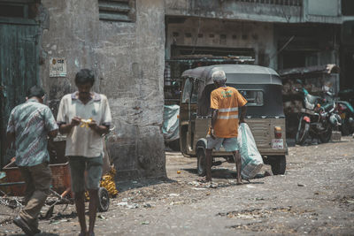 Rear view of people working on street against buildings