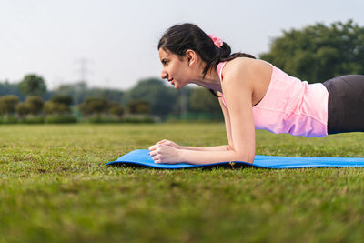 Young indian girl doing planks in the park. girl stretching and doing yoga in yoga mat. 