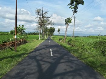 Road amidst field against sky