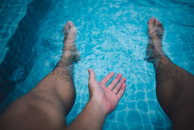 Low section of man relaxing in swimming pool