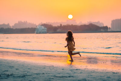 Woman standing at beach during sunset