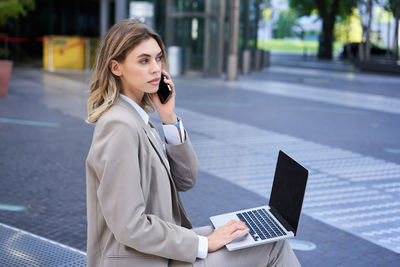 Young businesswoman using mobile phone while sitting in office