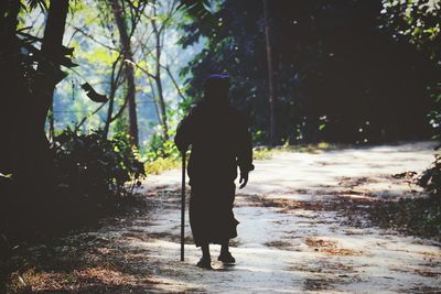 Rear view of man walking on footpath in forest