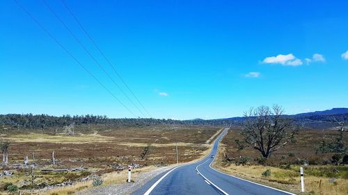 Road by landscape against blue sky
